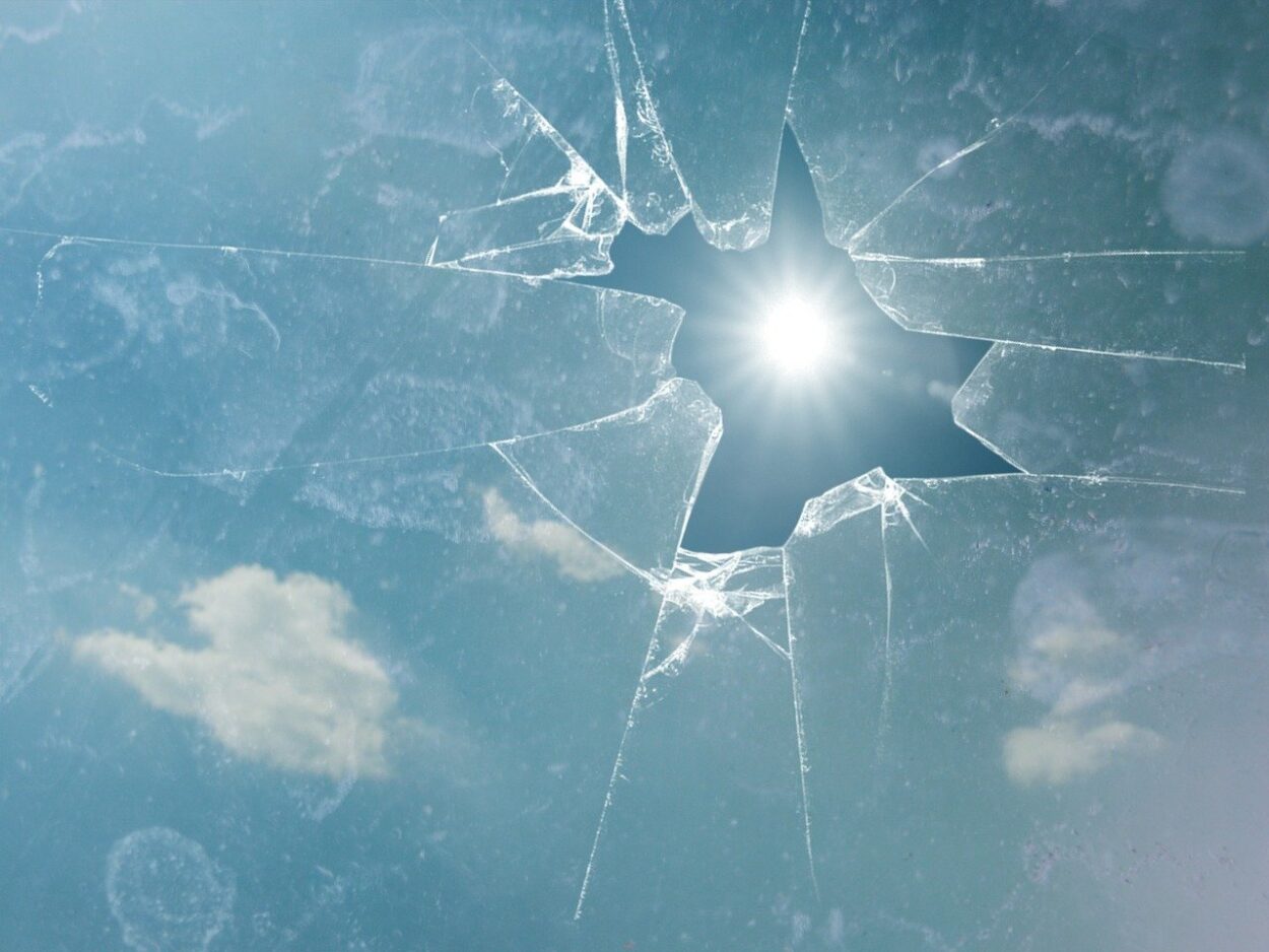 Broken glass with sun peeking through broken hole