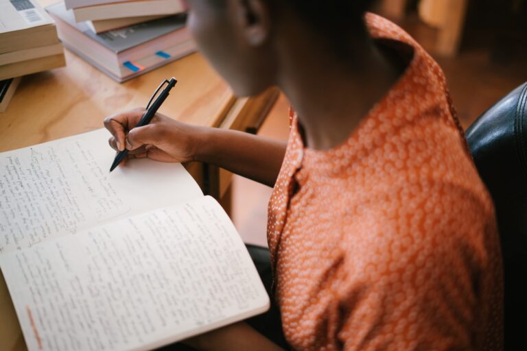 person sitting at desk writing in notebook