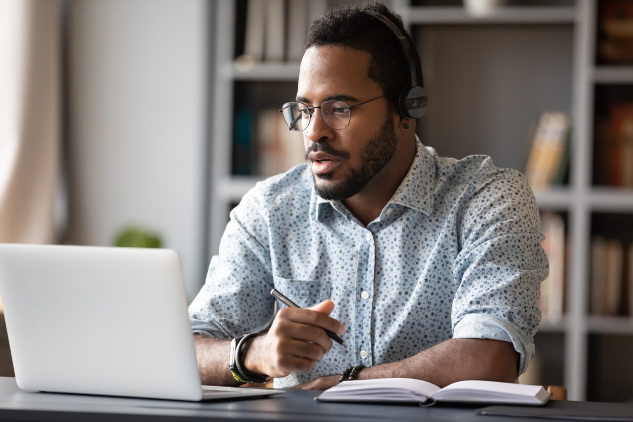 Focused African American man wear headphones in tele meeting