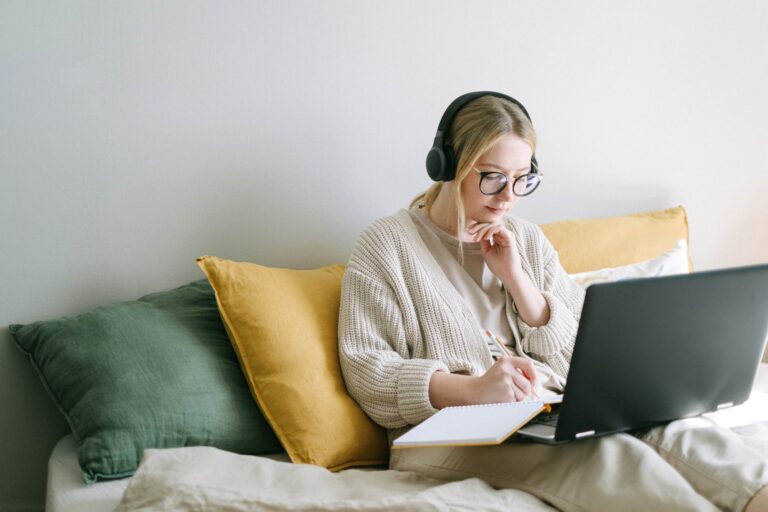 Student on couch, with headphone on at computer