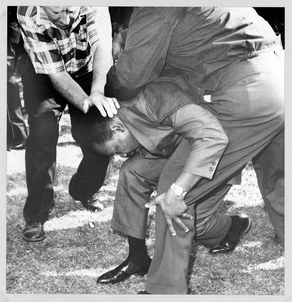 Chicago; Struck on the head by a rock thrown by a group of hecklers, Dr. Martin Luther King falls to one knee.