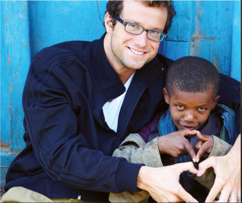 Markus Rogan has his arm around an Ethiopian child
