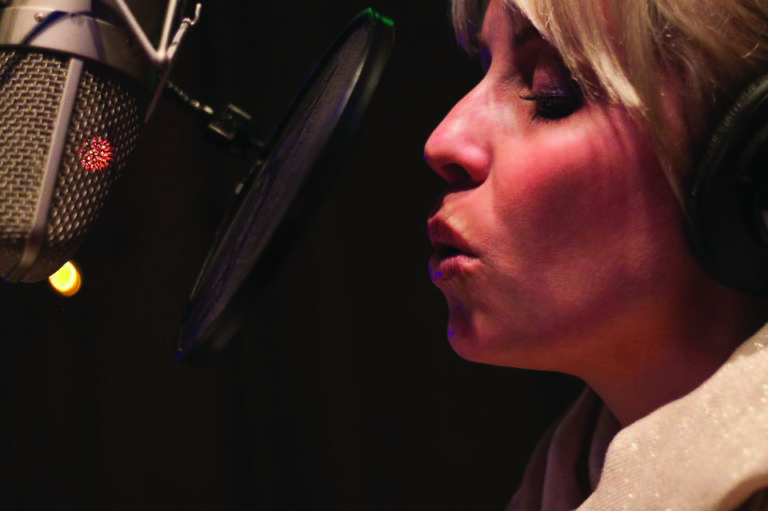 Darby Bailey singing into studio microphone.