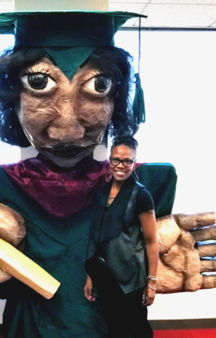 Ruffin stands next to a ten-foot tall puppet of Loretta Scott King wearing Antioch graduation regalia.