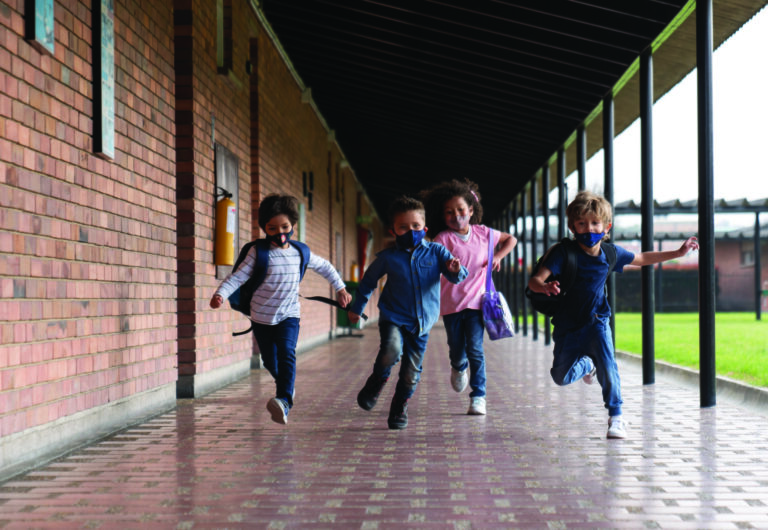 Children running at the school while wearing facemasks