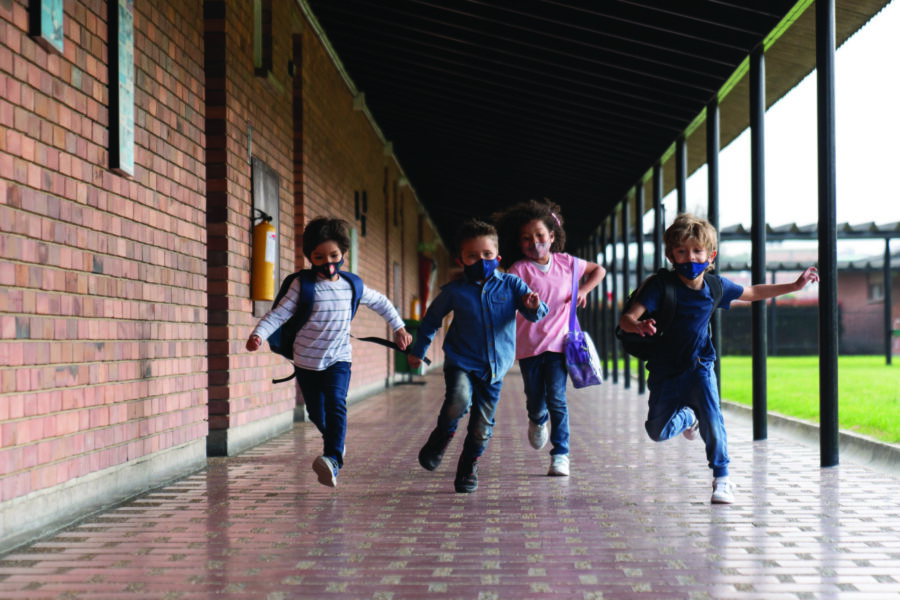 Children running at the school while wearing facemasks