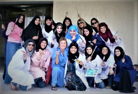 A group of women students wearing hijabs, posing for a class picture.