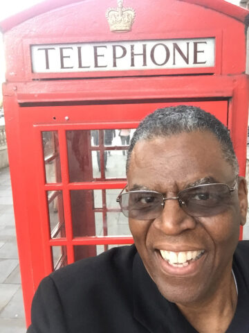 McMillian in front of a red telephone booth. 