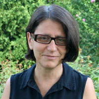 Lorraine Mangione standing in front of green shrubbery and trees.