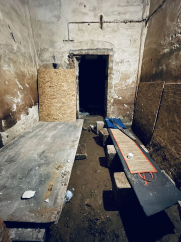A rough concrete room with plywood boards.