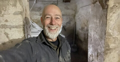 A bearded man smiling inside a bomb shelter.