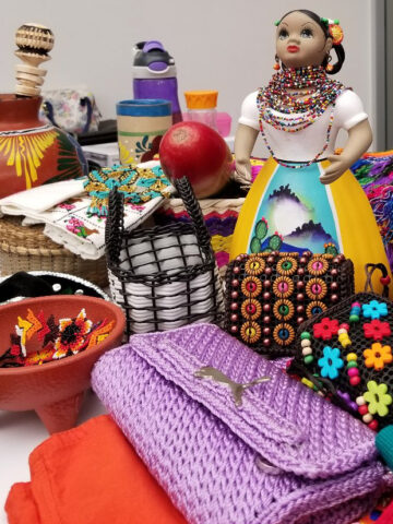 A table displaying Mexican items, such as a doll, purse, and various other objects.