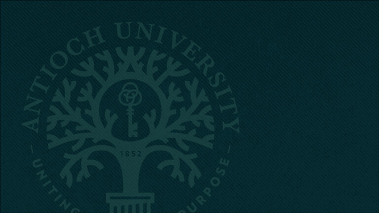 Dark green Antioch University seal with tree and key at center.