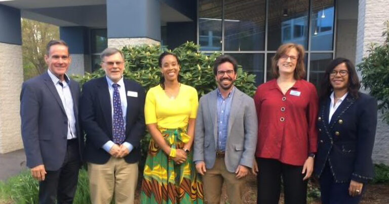 A photo of six people standing in front of a building.