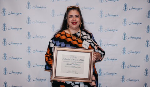 Photo of Ligiah Vilalobos in front of a step-and-repeat background holding an award.