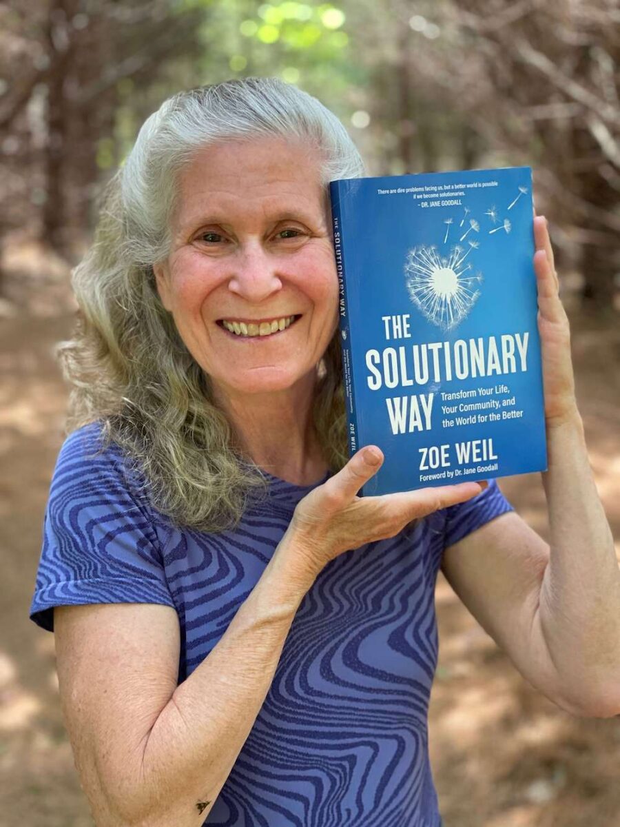 Zoe Weil smiling and holding her book the Soultionaty Way.