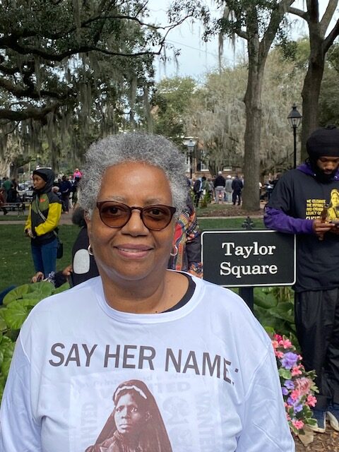 Fayth Parks standing outside in front of a sign that read Taylor Square and wearing a shirt that says Say Her Name