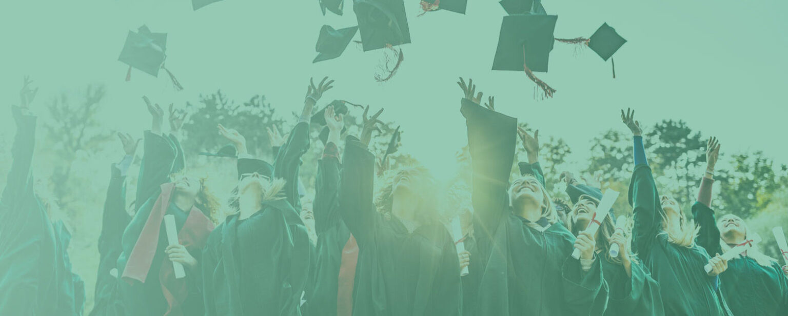 Group of graduates throwing caps in the air.