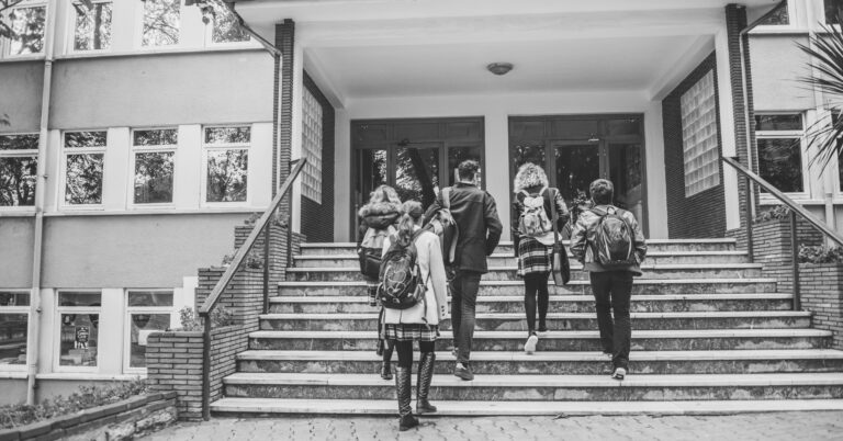 A black-and-white photo of students walking into a high school.