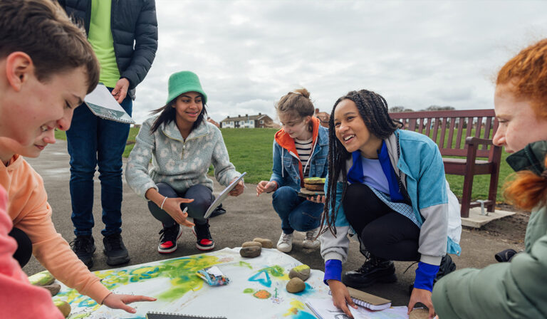 A group of young individuals collaborates around a map, discussing their plans and exploring new destinations together.