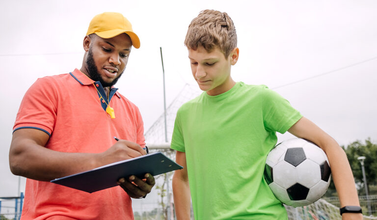 Athletic trainer working with student holding a soccerball