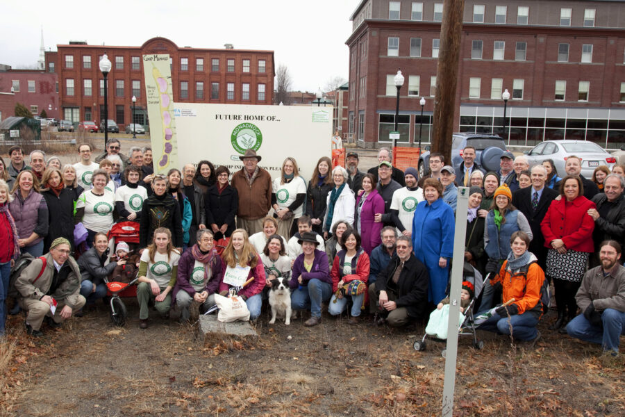 A diverse group of individuals gathered in front of the building site where the future Monadnock Co-op structure will be built.