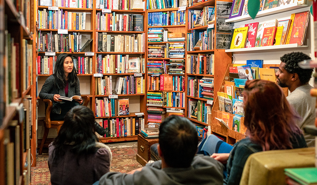 An author in a bookstore reading to a small audience seated in chairs.