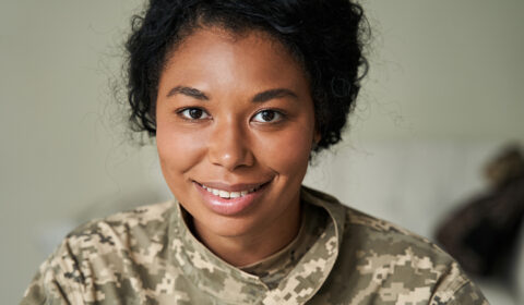 A woman in a military uniform smiles confidently at the camera, showcasing her pride and professionalism.