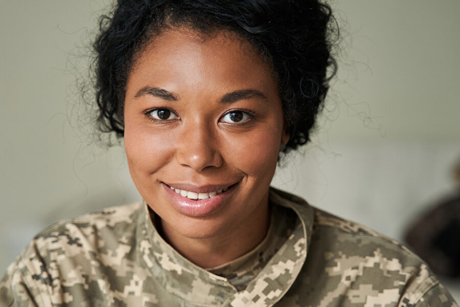 A woman in a military uniform smiles confidently at the camera, showcasing her pride and professionalism.
