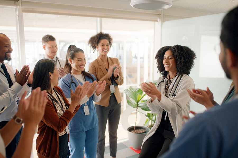 A team of professionals in an office, showing support by applauding each other.