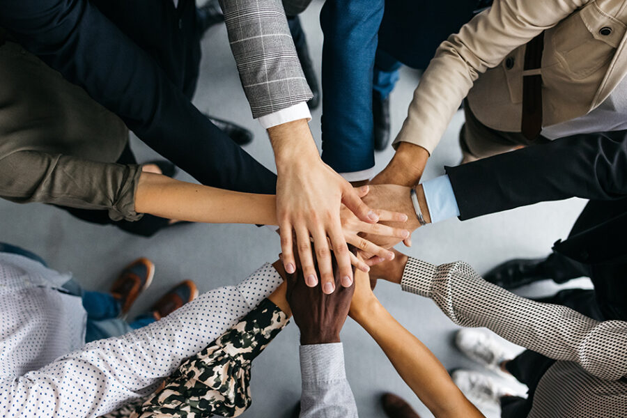 A diverse group of business people standing in a circle, joining hands in a show of unity and collaboration.