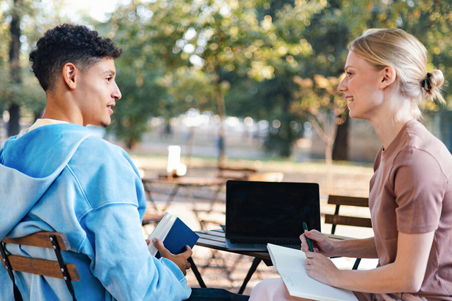 A man and woman engaged in conversation while seated at a table.