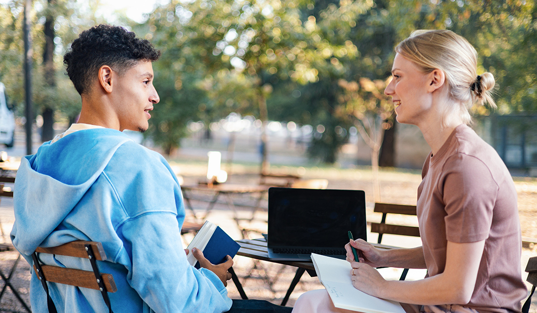 A man and woman engaged in conversation while seated at a table.