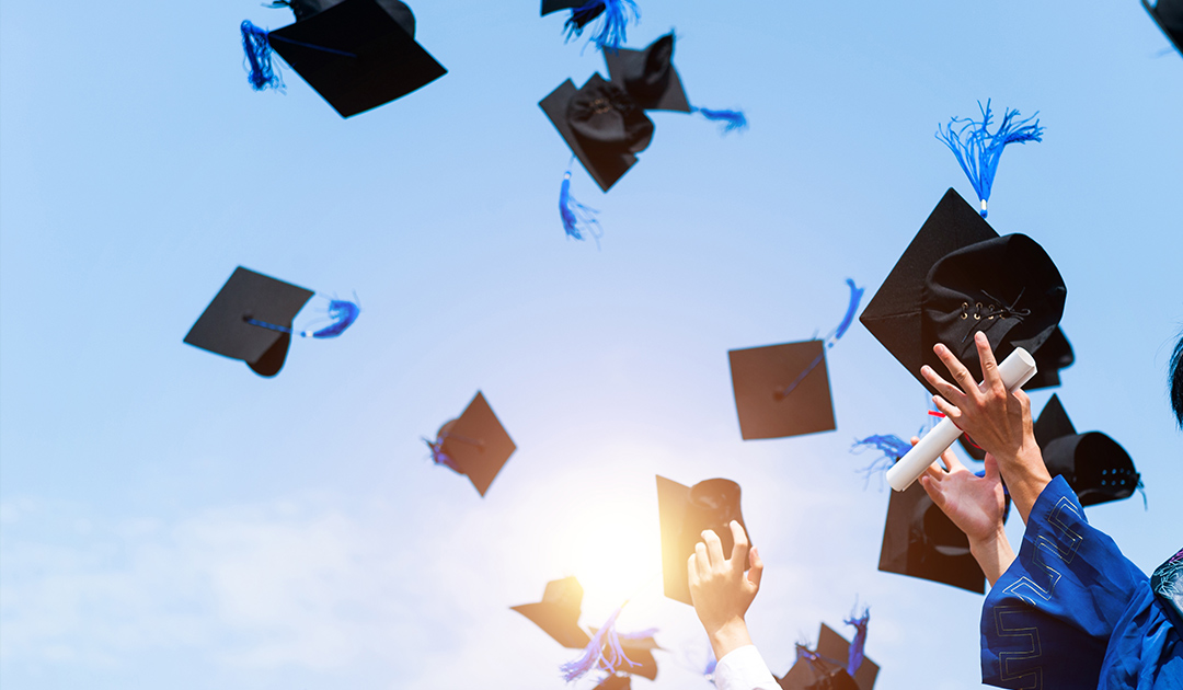 Blue sky and graduation caps being thrown into the air. Hands holding diplomas and hats.
