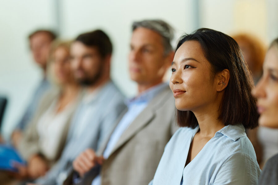 A woman sits in front of a group, engaging them with her presentation or discussion.