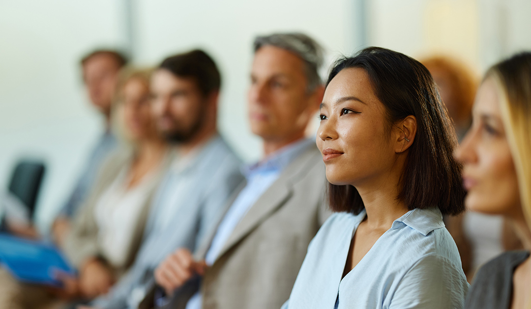 A woman sits in front of a group, engaging them with her presentation or discussion.
