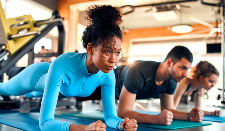 Several people engaged in push-ups on gym mats, showcasing teamwork and fitness.