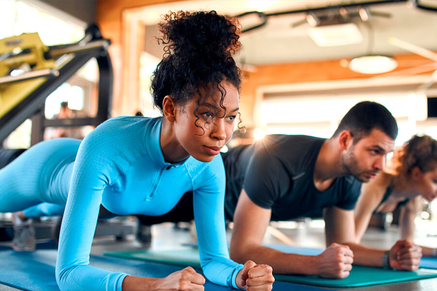 Several people engaged in push-ups on gym mats, showcasing teamwork and fitness.