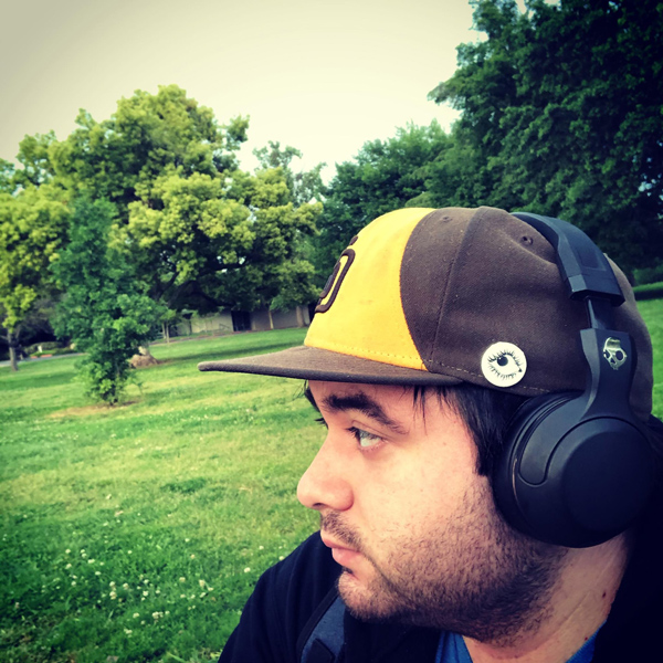 Man wearing headphones and a baseball cap in a park
