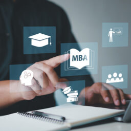 Person using a laptop with education icons, including an MBA book, graduation cap, and student figures
