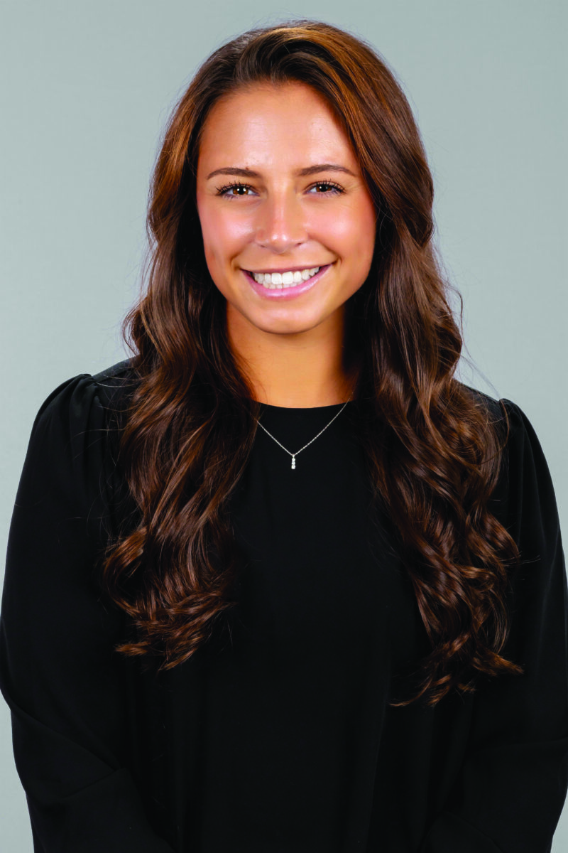 Samantha D’Anna, smiling women in black shirt with a silver necklace and long brown hair, silver necklace, smile, long brown hair