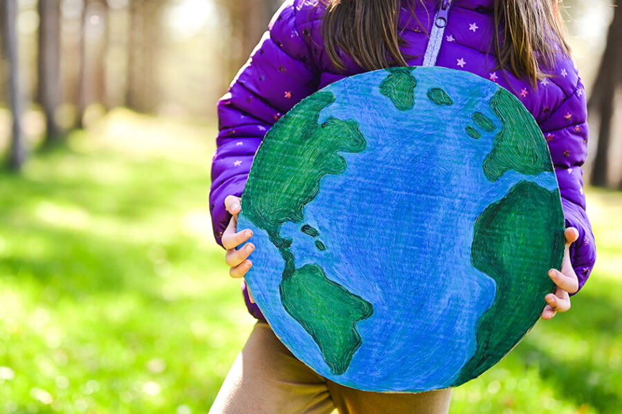 Child holding a hand-drawn globe in a sunlit park