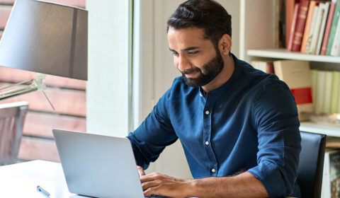 Man working on a laptop at a desk in a home office